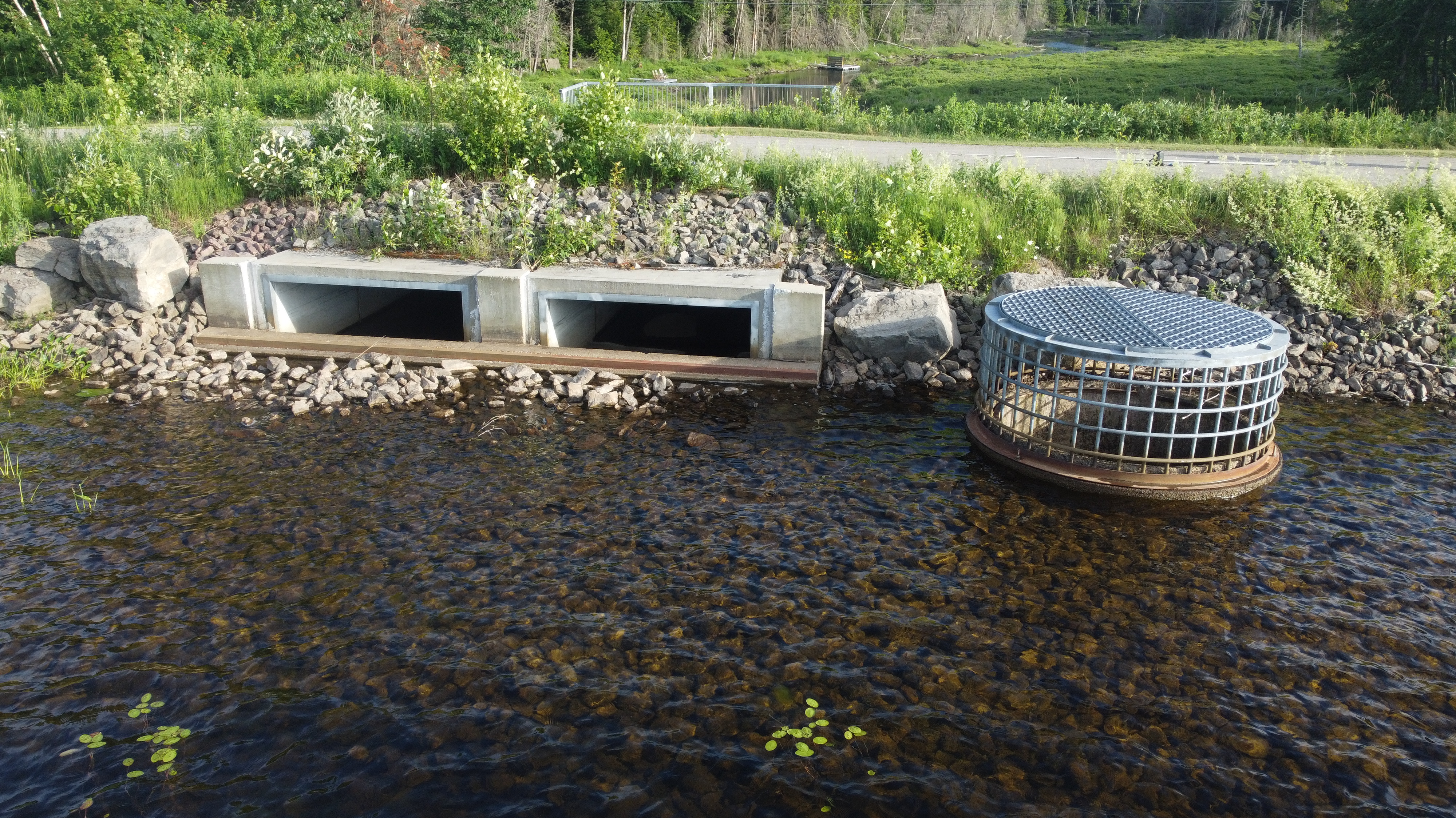 Ouvrage de contrôle de l’eau avec structures en béton et enrochement visible dans un cours d’eau au Québec