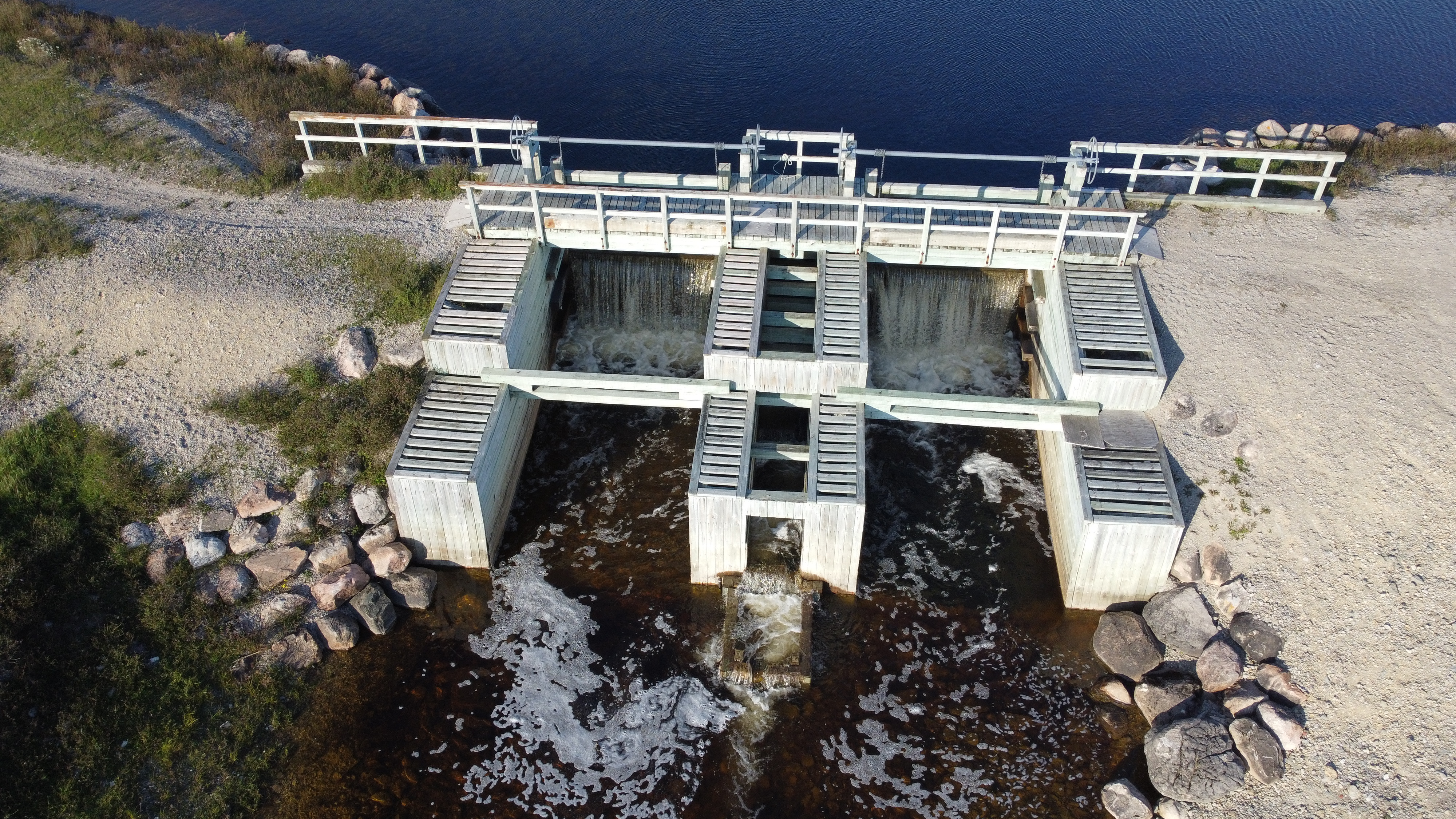 Vue aérienne d’un barrage retenant un plan d’eau entouré de forêt et d’un chemin d’accès au Québec