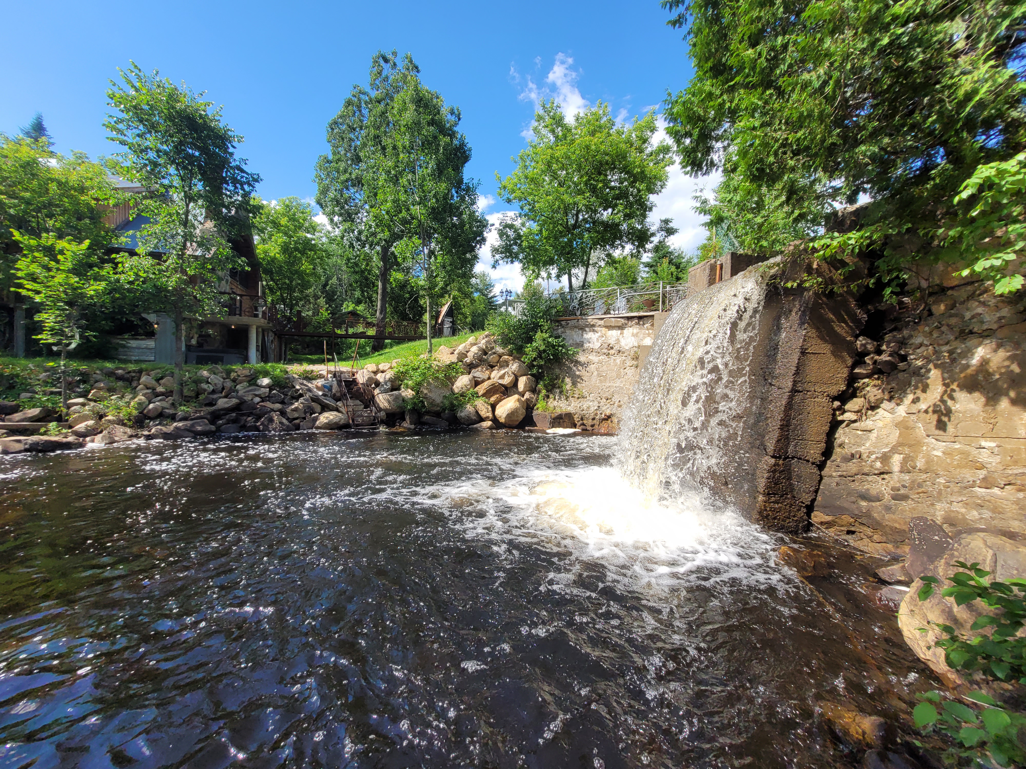 Vue verticale d’un ouvrage de retenue séparant un plan d’eau et un écoulement naturel en milieu boisé au Québec